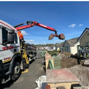 Grab hire wagon picking up rubble from residential garden.