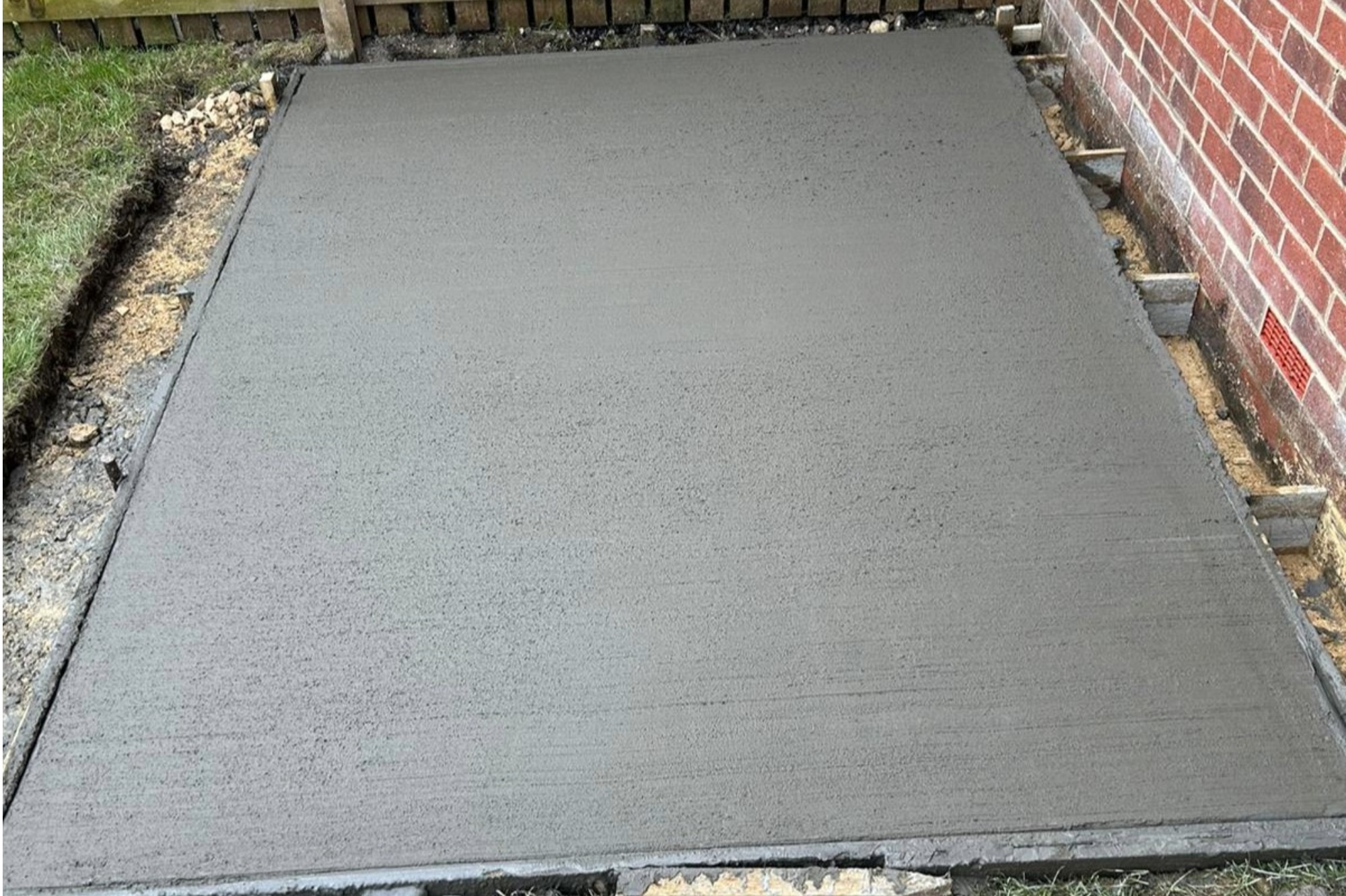 Close up of fresh concrete base for shed in a garden.